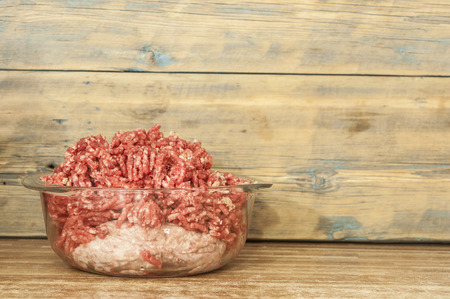 raw beef ground meat in glass plate on a rustic wooden tableの写真素材
