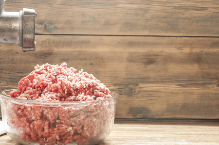 raw beef ground meat in glass plate on a rustic wooden tableの写真素材