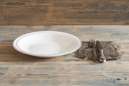 Empty plate, knife and fork over wooden table background. View from top with copy space.