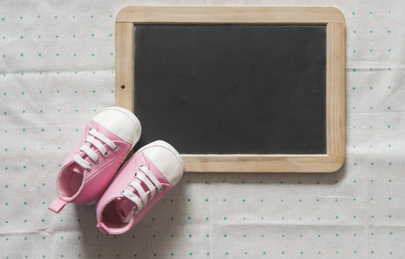 Cute little baby shoes on green polka dot background, top viewの写真素材