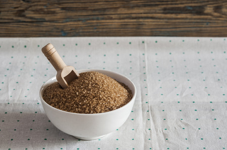 Brown sugar in ceramic bowl with a wooden scoop on the tableの写真素材