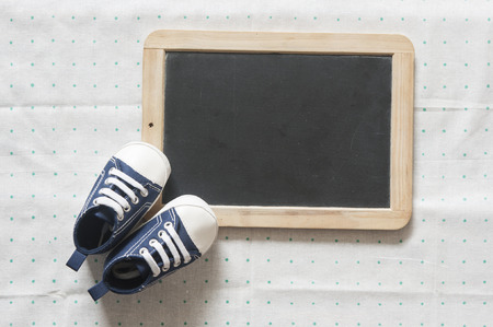 Cute little baby shoes on green polka dot background, top viewの写真素材