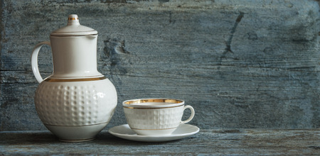 ceramic coffee pot with white coffee cup and saucer on wood tableの写真素材
