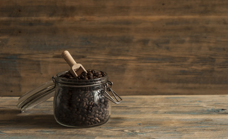 Roasted coffee beans in glass jars on wood tableの写真素材