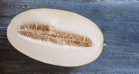 Green melon with half of one put on the wood backgroundの写真素材