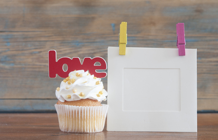 Text love and cupcake with heart shapes on wooden backgroundの写真素材