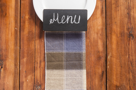 Restaurant menu design. Restaurant menu with empty plate on wooden background with colorful napkin....
