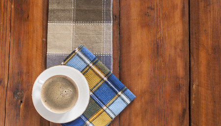 White cup of coffee with colorful napkin on old wooden table. Top view point.の写真素材