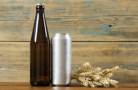 blank metallic can and glass bottle of beer on a wooden backgroundの写真素材