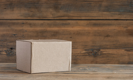 Closed cardboard package box presented on wooden table