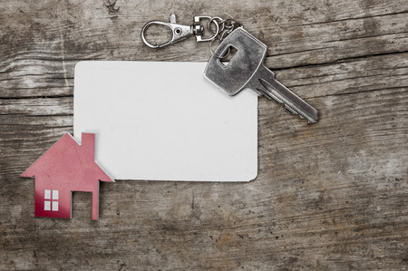 Silver key and blank business card on wooden background. Real estate concept.の写真素材