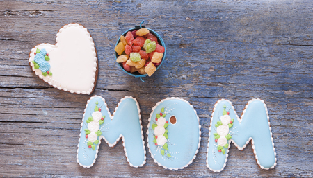 Mother's day Greeting card concept. I love you mom. Letters mom in the form of a cookie, wooden background. Top view.の写真素材