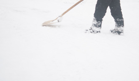 winter and cleaning concept - closeup of man shoveling snow from drivewayの写真素材