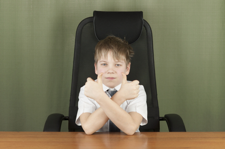 Portrait of stylish business child sitting at workplace. Cute caucasian boy imitating businessperson or office workeの写真素材