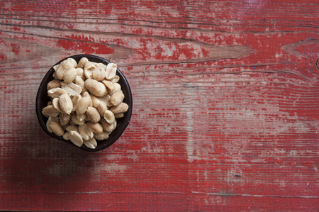 Pile salted and marinated peanuts on  wooden background, top view 