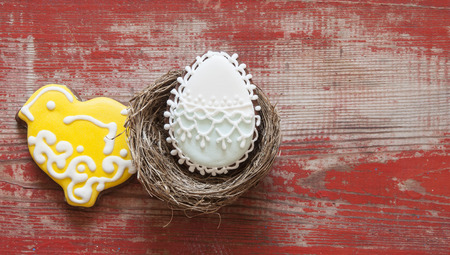 Colorful easter cookies in nest on wooden background