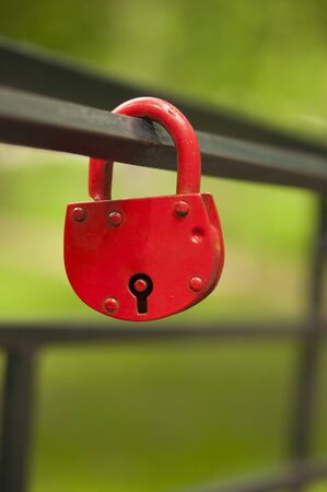 A red metal lock hangs on a rusty metal pipes の写真素材
