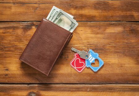 Key home and leather wallet on old wooden table. の写真素材