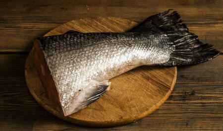 fresh salmon tail on a cutting kitchen board surfaceの写真素材