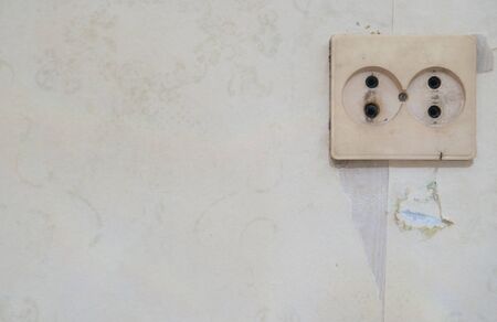 Old white electric socket on wall. Cracked concrete vintage wall background, old wall.