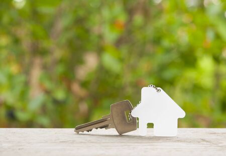 House key on a house shaped keychain on natural background. Real estate concept