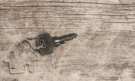 Symbol of the house with silver key on vintage wooden background. Real estate concept