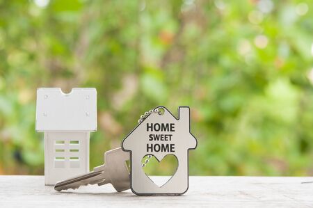 House key on a house shaped keychain on natural background. Real estate concept