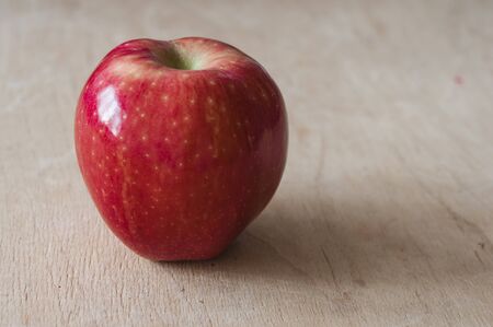 one red apple on wood table