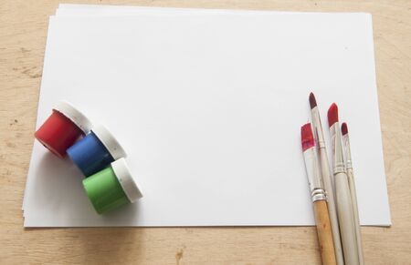Blank piece of paper with brushes and watercolors on kid's desk, top view with copy spaceの写真素材