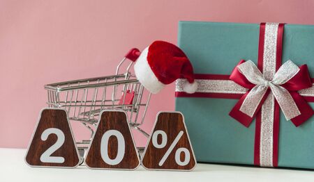 Big sales 20%, twenty percents with Santa hat and christmas gift box over pink background. Christmas...