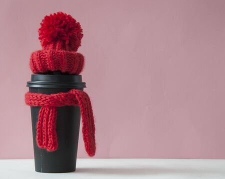 knitted red scarf and hat on paper cup of coffee