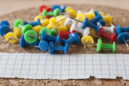 Group of colorful push pins on cork bulletin board