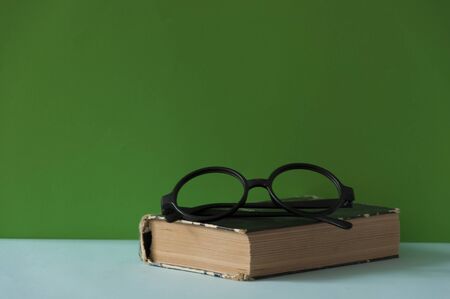 Book and glasses on colorful background with space for text