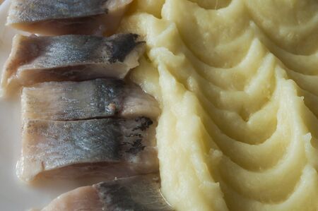 Slices of mild-cured herring with potatoes served on white plateの写真素材