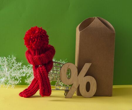 Winter sale and shopping concept. Red knitted hat and scarf with wooden sign percent over white backgroundの写真素材