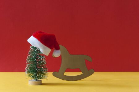 Santa Claus hat and Christmas tree with children toy rocking horse on colorful paper backgroundの写真素材