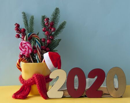 Christmas or new year card. Christmas candy canes in yellow mug with berries holly branches and...