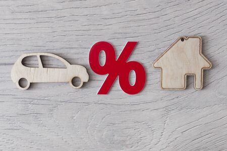 Wooden car and house model with percent sign. The concept of low interest rates on mortgage loans or rentals. The percentage of real estate sales. Tax interest. Loan secured.の写真素材