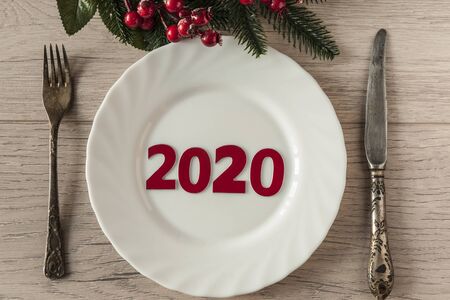 2020 New year concept on empty white plate, fork and knife on wooden tabletop. Top view, copy space, Table setting. background for menu, layoutの写真素材