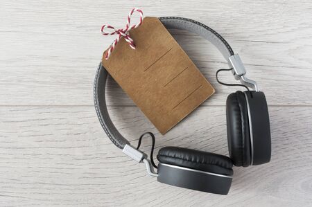 Top view of an black audio headphone with blank price tag on white wooden backgroundの写真素材
