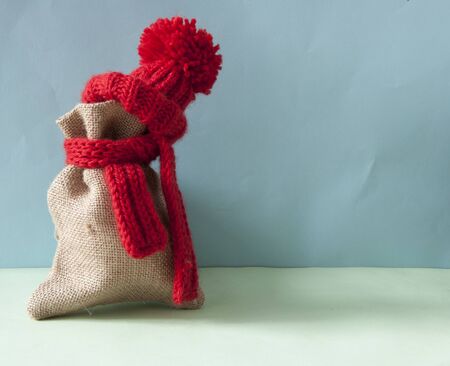 a red knitted winter hat with scarf on burlap sackの写真素材