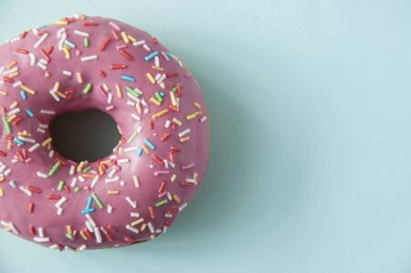 one pink sweet doughnut on blue paper backgroundの写真素材