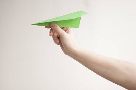 Woman hand throwing paper plane over white backgroundの写真素材