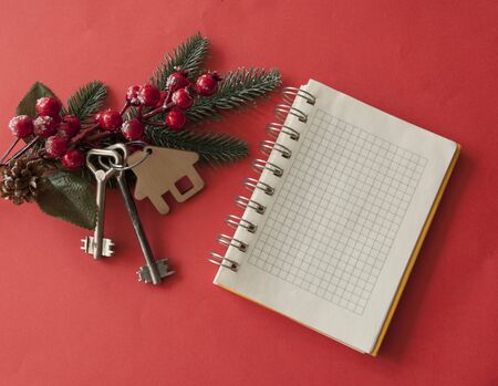 Beautiful Christmas background: decorative house and key to the lock on red background, flat lay. Space for text. Concept of finance and housing loans. Top viewの写真素材