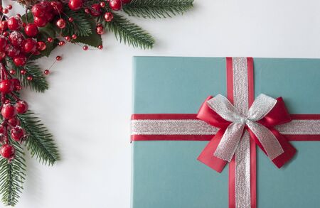 Christmas background with fir twigs, red berriesand gift box with copy-space on white paper...