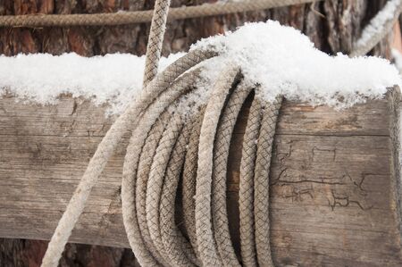 rope covered snow tied around a wooden logの写真素材