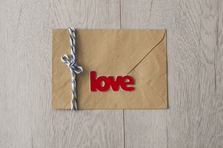  Valentineâs Day card. Brown color envelope and word "love" with wax seal on white wood tableの写真素材