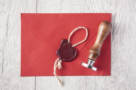 wax seal with red envelope on white wooden table with rough texture. Top view