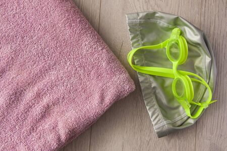 Swimming cap, goggles and towel on wooden table. Top view. Space for textの写真素材