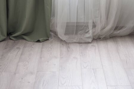 White satin sparse curtain with bright sunlight and wooden floor.の写真素材